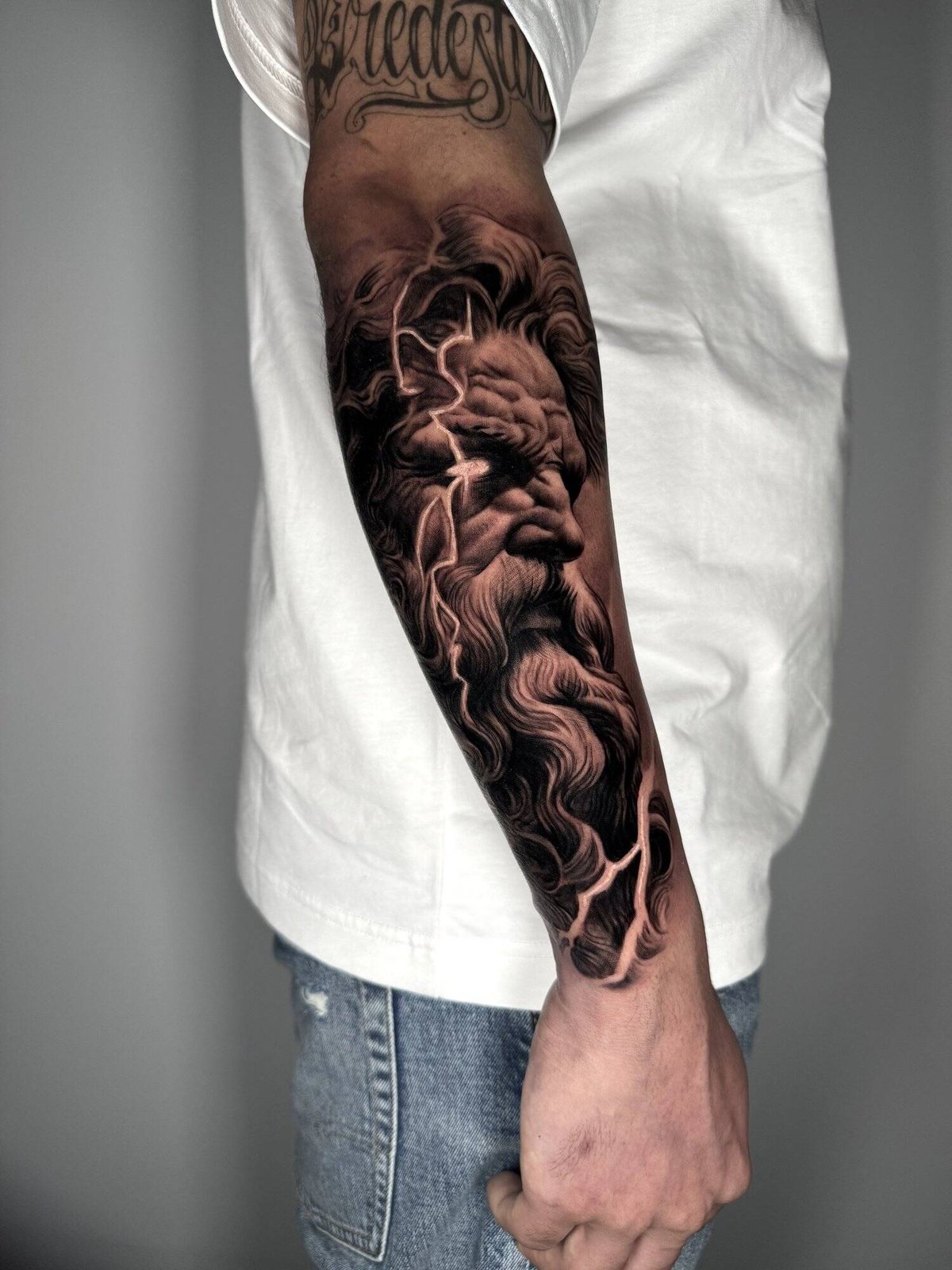 Black and grey realism forearm sleeve of a bearded classical figure surrounded by cloud and smoke